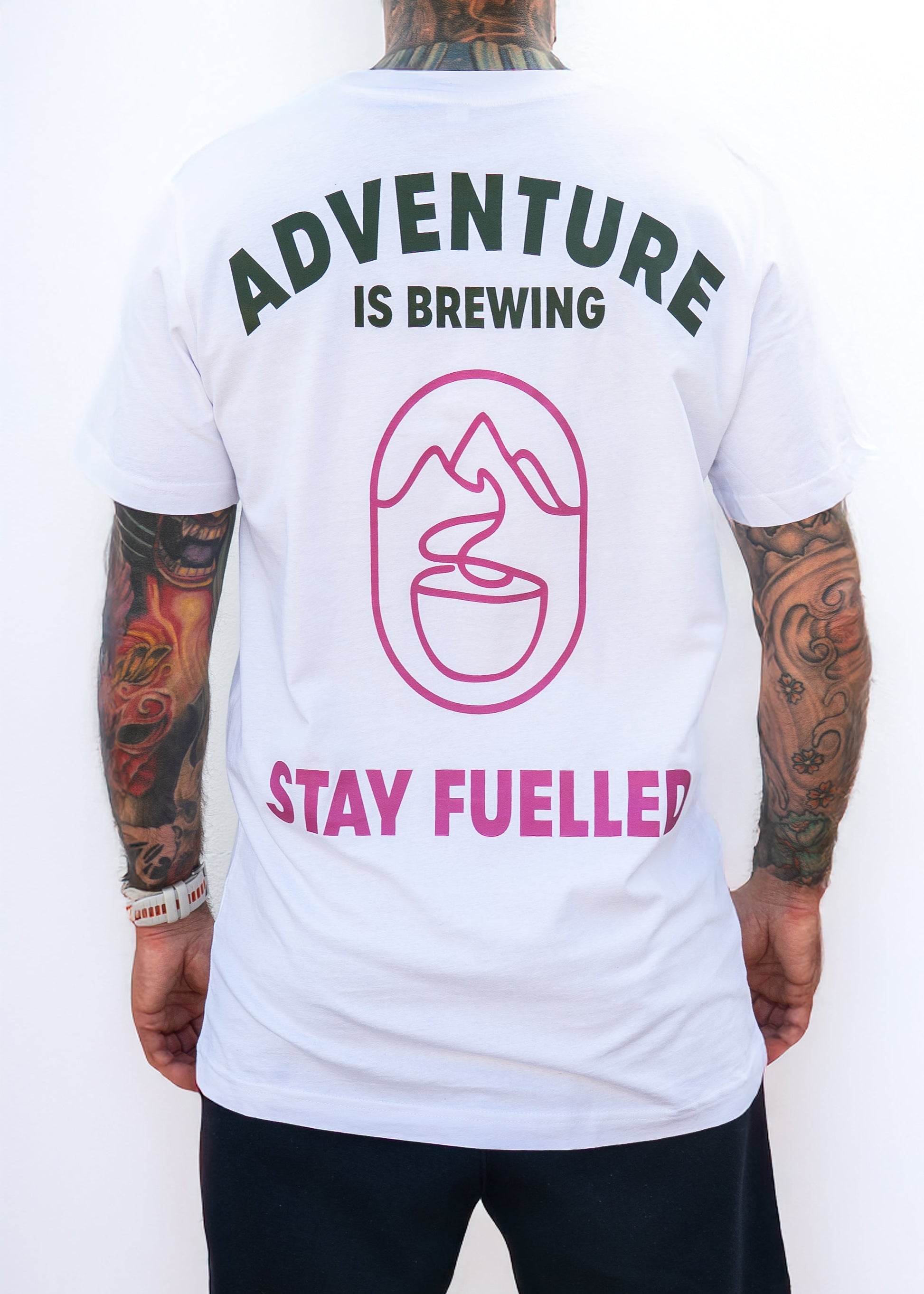 Person wearing a white t-shirt with 'Adventure is Brewing, Stay Fuelled' text and graphics on the back.