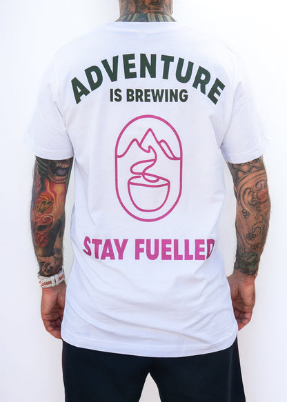 Person wearing a white t-shirt with 'Adventure is Brewing, Stay Fuelled' text and graphics on the back.