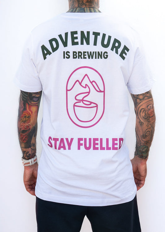 Person wearing a white t-shirt with 'Adventure is Brewing, Stay Fuelled' text and graphics on the back.
